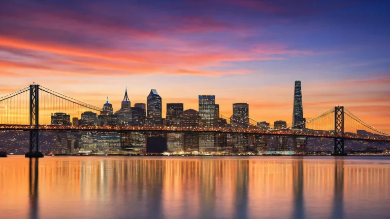 A serene Oakland Bay Bridge scene on a desktop or PC, with the San Francisco sky's deep blues, vibrant oranges, and warm yellows